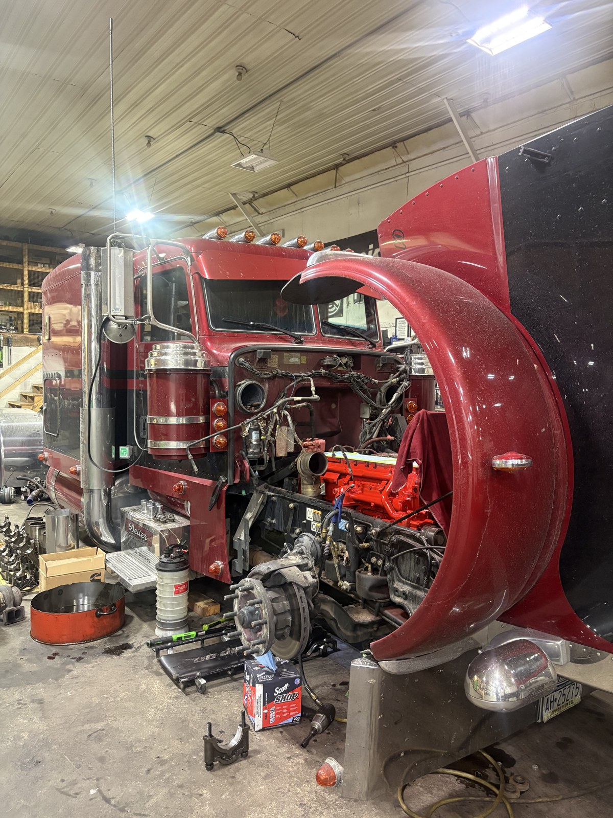 Red heavy-duty truck undergoing engine work in the Hess repair shop